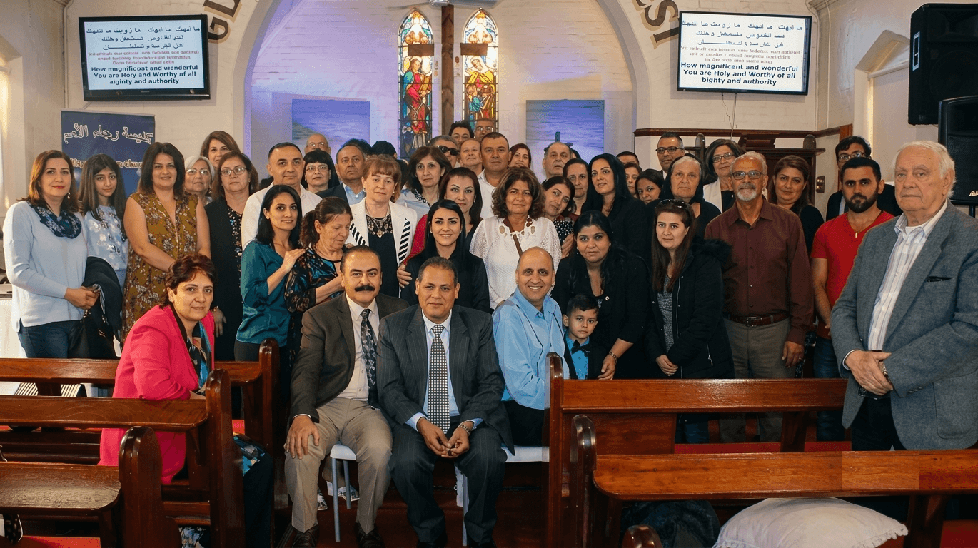 Large group of people posing for a photo inside a church with stained glass windows.